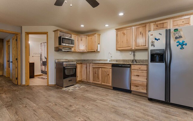 kitchen featuring appliances with stainless steel finishes, light brown cabinets, light hardwood / wood-style floors, light stone countertops, and ceiling fan