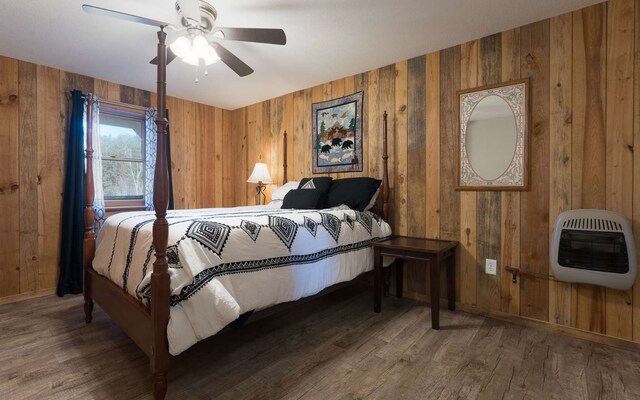 bedroom with wood walls, ceiling fan, and wood-type flooring