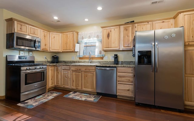 kitchen with dark hardwood / wood-style flooring, light brown cabinets, sink, dark stone countertops, and appliances with stainless steel finishes