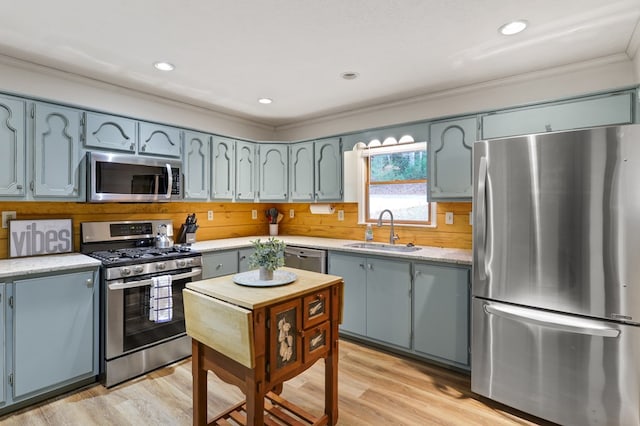 kitchen featuring backsplash, stainless steel appliances, crown molding, sink, and light hardwood / wood-style flooring