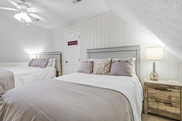 bedroom with ceiling fan, carpet floors, a textured ceiling, vaulted ceiling, and wooden walls