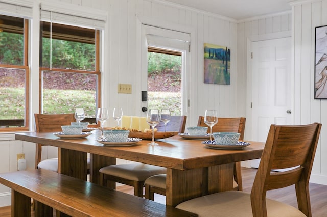 dining room featuring wood walls, wood-type flooring, and ornamental molding