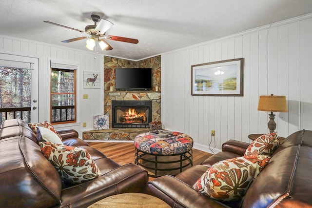 living room featuring ceiling fan, a fireplace, wood-type flooring, and wooden walls