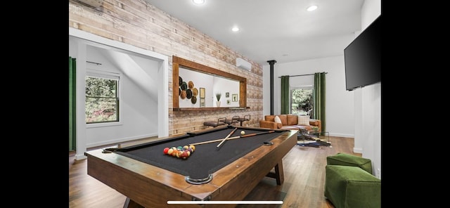 recreation room with plenty of natural light, hardwood / wood-style floors, brick wall, and billiards