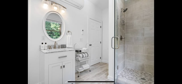 bathroom featuring a shower with shower door, wood-type flooring, vanity, and a wall mounted AC