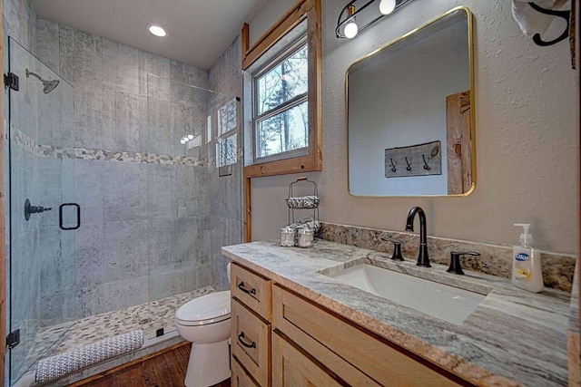 full bathroom with toilet, a shower stall, wood finished floors, and vanity