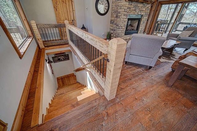 stairway featuring a stone fireplace and wood-type flooring