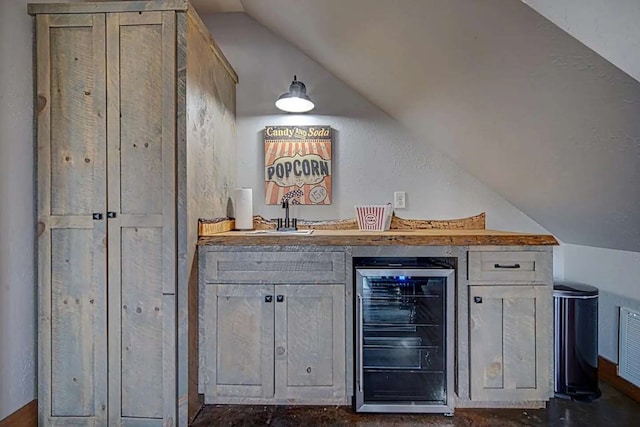 bar with beverage cooler, wet bar, a sink, and lofted ceiling