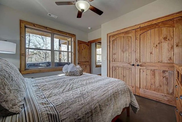 bedroom with visible vents, dark carpet, and a ceiling fan