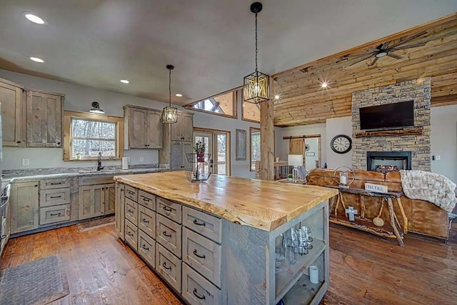 kitchen featuring a center island, decorative light fixtures, open floor plan, a sink, and wood finished floors