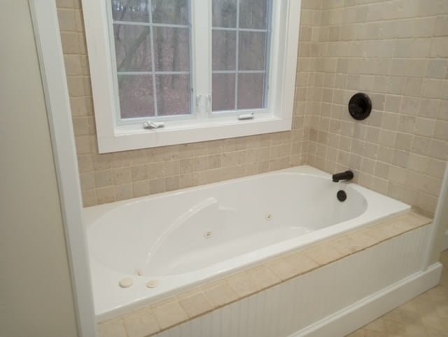 bathroom with tile patterned flooring and tiled tub