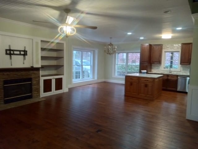 kitchen with a healthy amount of sunlight, stainless steel dishwasher, a center island, and a stone fireplace