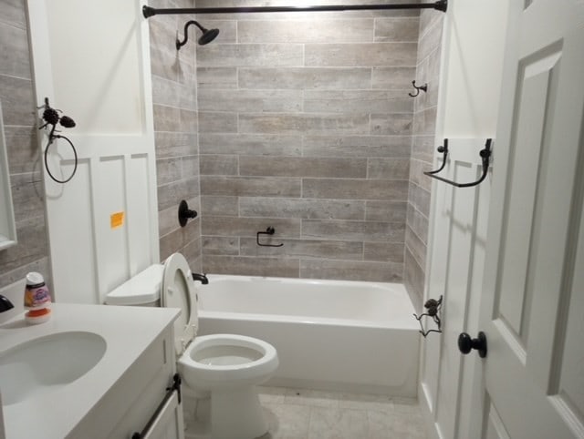 full bathroom featuring vanity, tiled shower / bath combo, and toilet