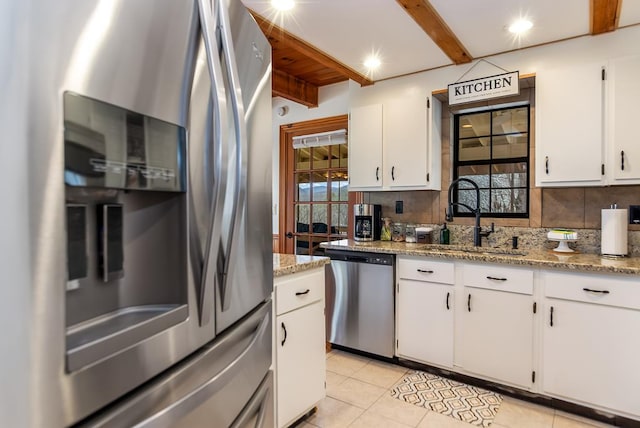 kitchen with stainless steel appliances, beamed ceiling, tasteful backsplash, light tile patterned flooring, and white cabinetry