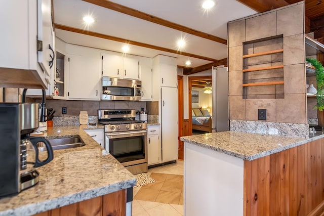 kitchen featuring appliances with stainless steel finishes, open shelves, tasteful backsplash, light stone countertops, and beamed ceiling