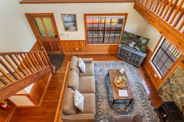 living room with wood finished floors, wainscoting, healthy amount of natural light, stairs, and wood walls