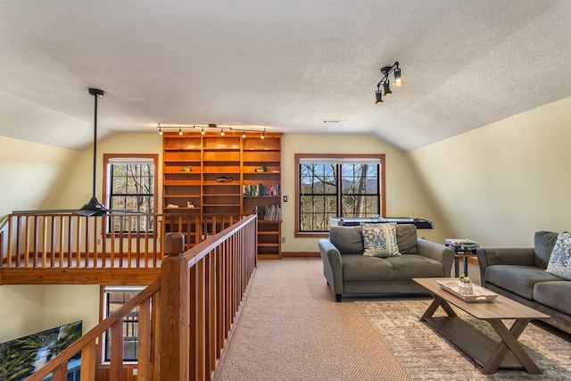 living room with track lighting, vaulted ceiling, carpet, healthy amount of natural light, and baseboards