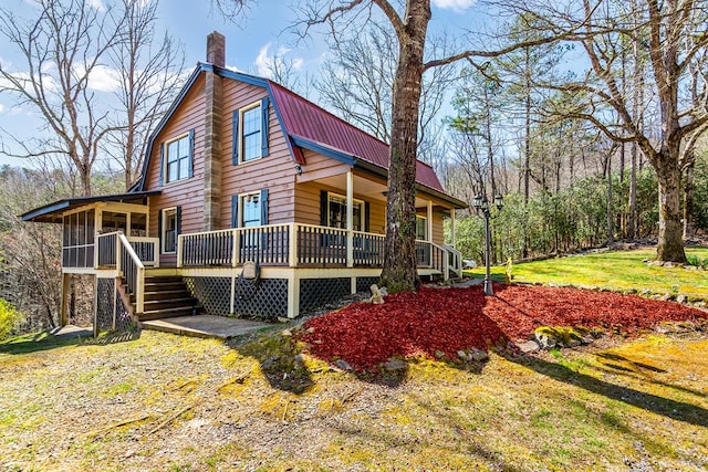view of side of property with a chimney, metal roof, a sunroom, a gambrel roof, and stairs