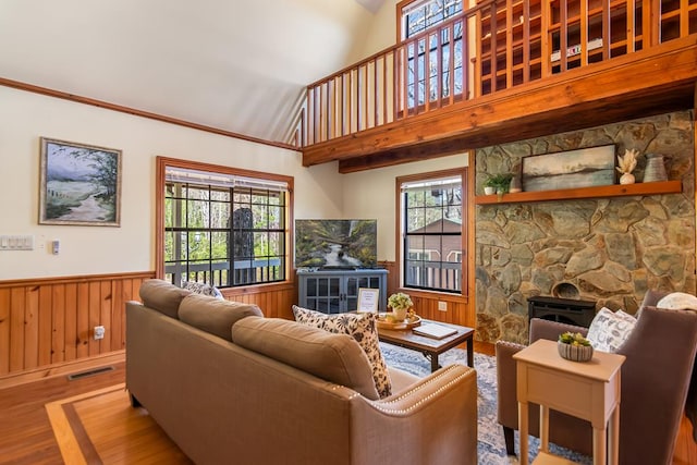 living area with wood finished floors, a wainscoted wall, healthy amount of natural light, a fireplace, and lofted ceiling