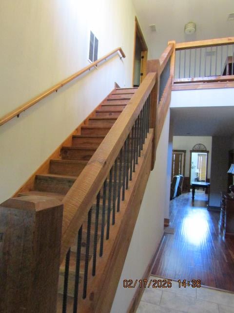 stairs with hardwood / wood-style flooring and a high ceiling