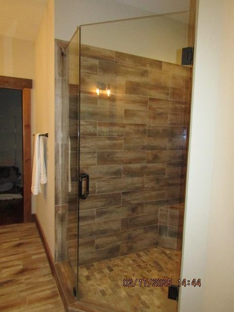 bathroom with hardwood / wood-style flooring and a shower with door