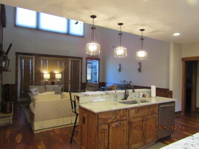 kitchen with sink, a center island with sink, stainless steel dishwasher, and pendant lighting