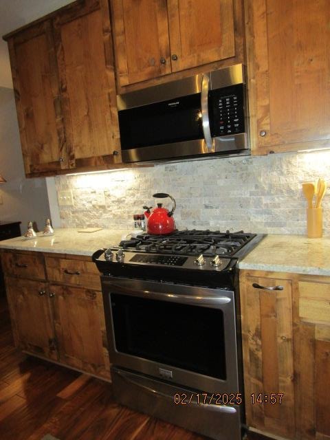 kitchen with stainless steel appliances, dark hardwood / wood-style floors, and backsplash