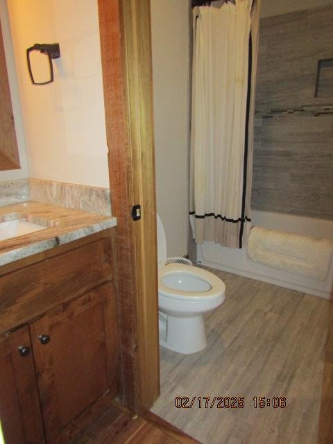 full bathroom featuring toilet, hardwood / wood-style flooring, shower / bath combination with curtain, and vanity