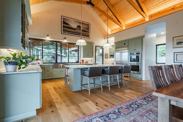 kitchen featuring green cabinets, beamed ceiling, light wood-style floors, and appliances with stainless steel finishes