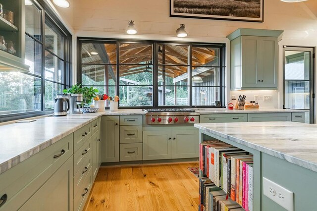 kitchen featuring green cabinetry, light stone countertops, light wood-type flooring, and stainless steel gas stovetop