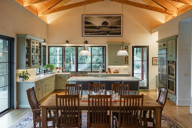 dining room with beam ceiling, wooden ceiling, high vaulted ceiling, and light wood-style floors