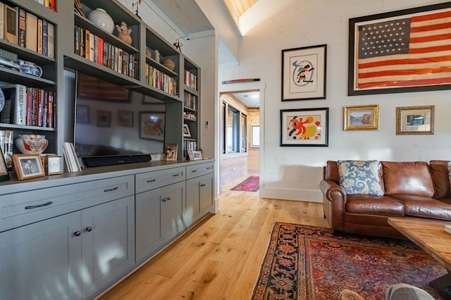 sitting room with baseboards, light wood-style floors, and vaulted ceiling