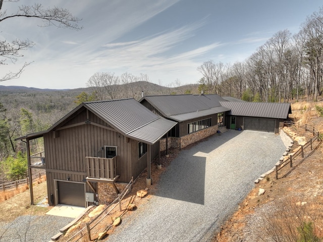 rustic home with a garage, fence, board and batten siding, gravel driveway, and metal roof