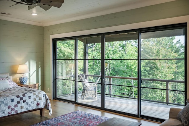 bedroom with wooden walls, wood finished floors, visible vents, recessed lighting, and access to exterior