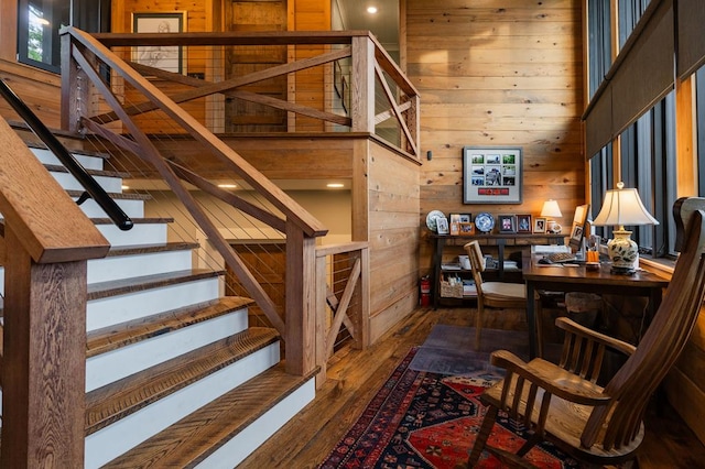 stairway with hardwood / wood-style flooring, wooden walls, and a high ceiling