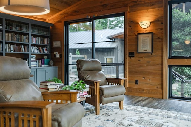 living area with wood finished floors, wood walls, and vaulted ceiling