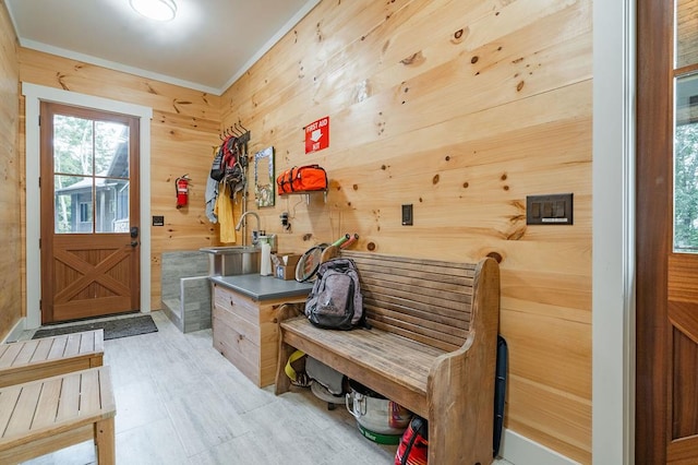 mudroom featuring a sink, wooden walls, and ornamental molding