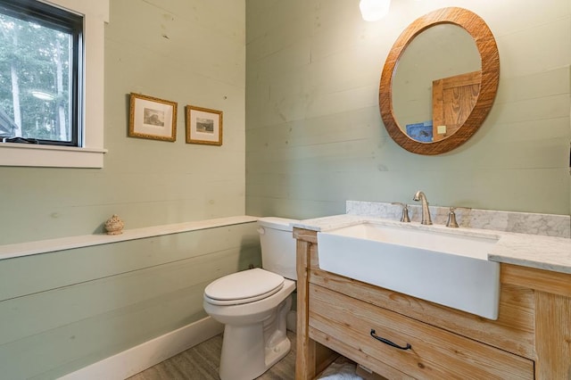 half bath featuring vanity, toilet, and wood finished floors