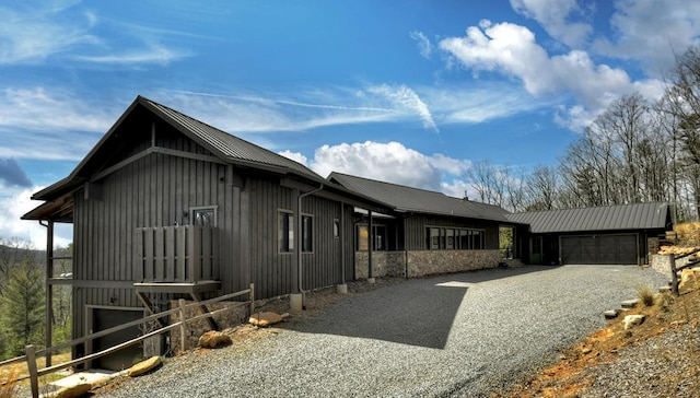 view of front of home featuring an attached garage, metal roof, gravel driveway, and board and batten siding