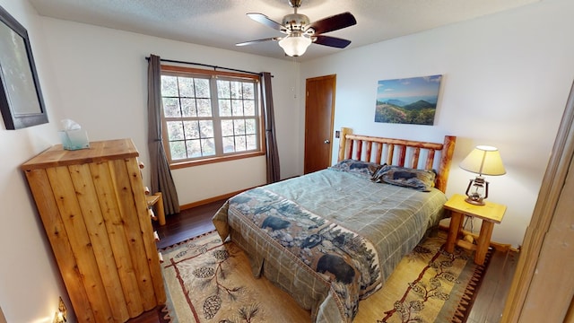 bedroom with ceiling fan, wood-type flooring, and a textured ceiling