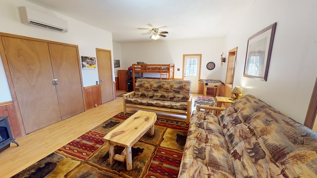 living room featuring a wall mounted air conditioner, light hardwood / wood-style floors, and ceiling fan