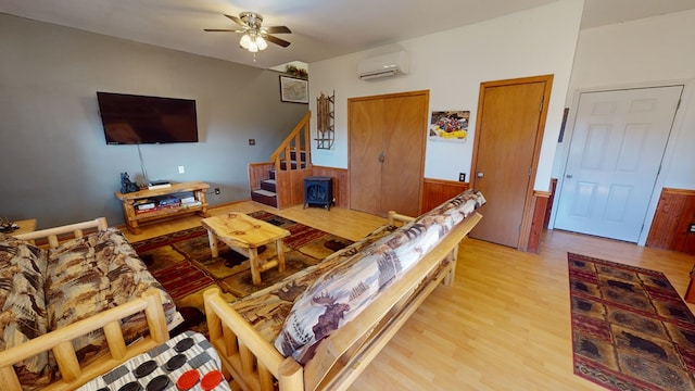 living room with hardwood / wood-style flooring, ceiling fan, and a wall mounted air conditioner