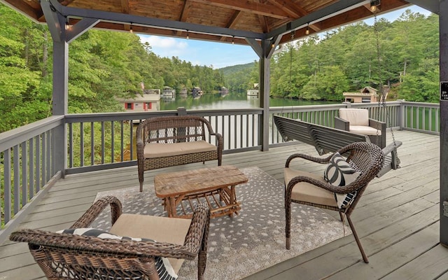 wooden deck with a water view, an outdoor hangout area, and a gazebo