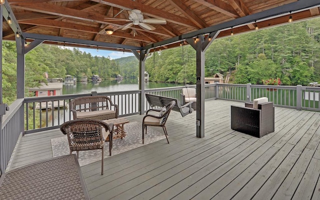 wooden terrace with a gazebo, an outdoor hangout area, ceiling fan, and a water view