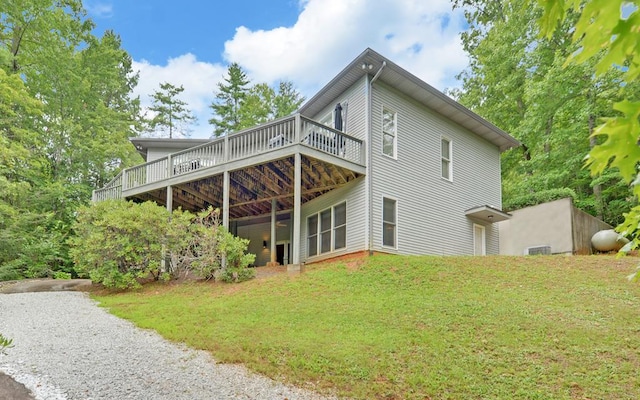 back of property featuring a wooden deck and a yard