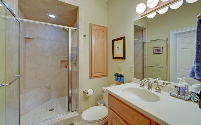 bathroom with vanity, a shower with door, and toilet