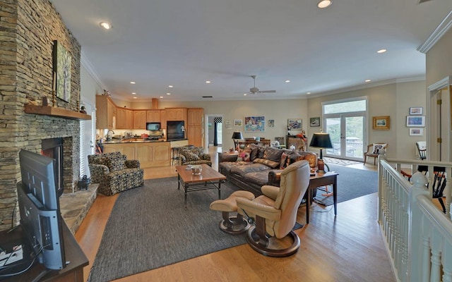 living room with french doors, sink, light hardwood / wood-style flooring, ornamental molding, and a fireplace