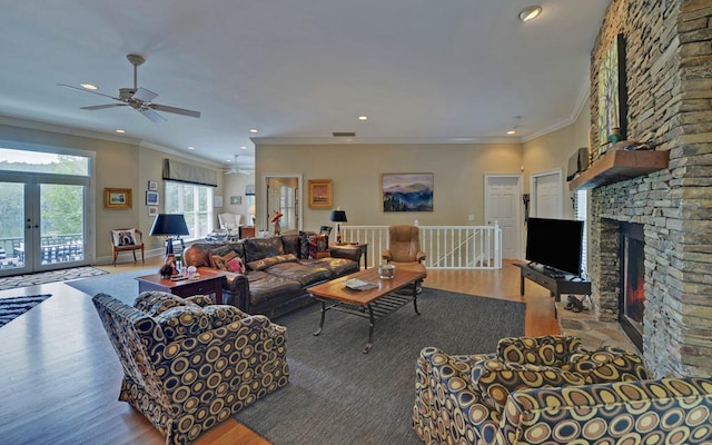 living room featuring french doors, ornamental molding, a fireplace, and light wood-type flooring