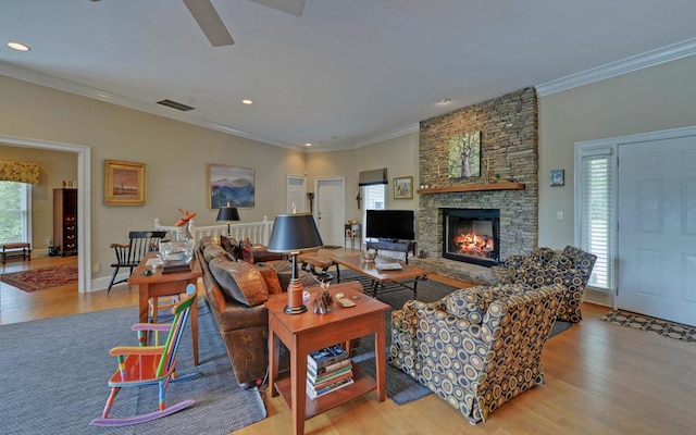 living room featuring crown molding, ceiling fan, a fireplace, and light hardwood / wood-style floors