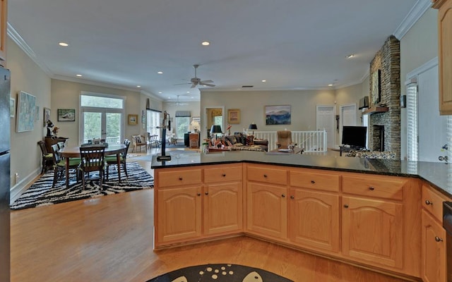 kitchen featuring kitchen peninsula, a fireplace, ceiling fan, light hardwood / wood-style floors, and crown molding